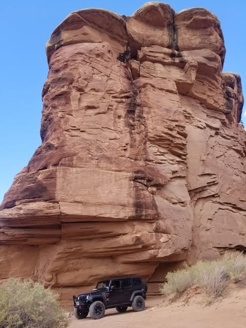 Towering red sandstone formation above a Jeep on Elephant Hill